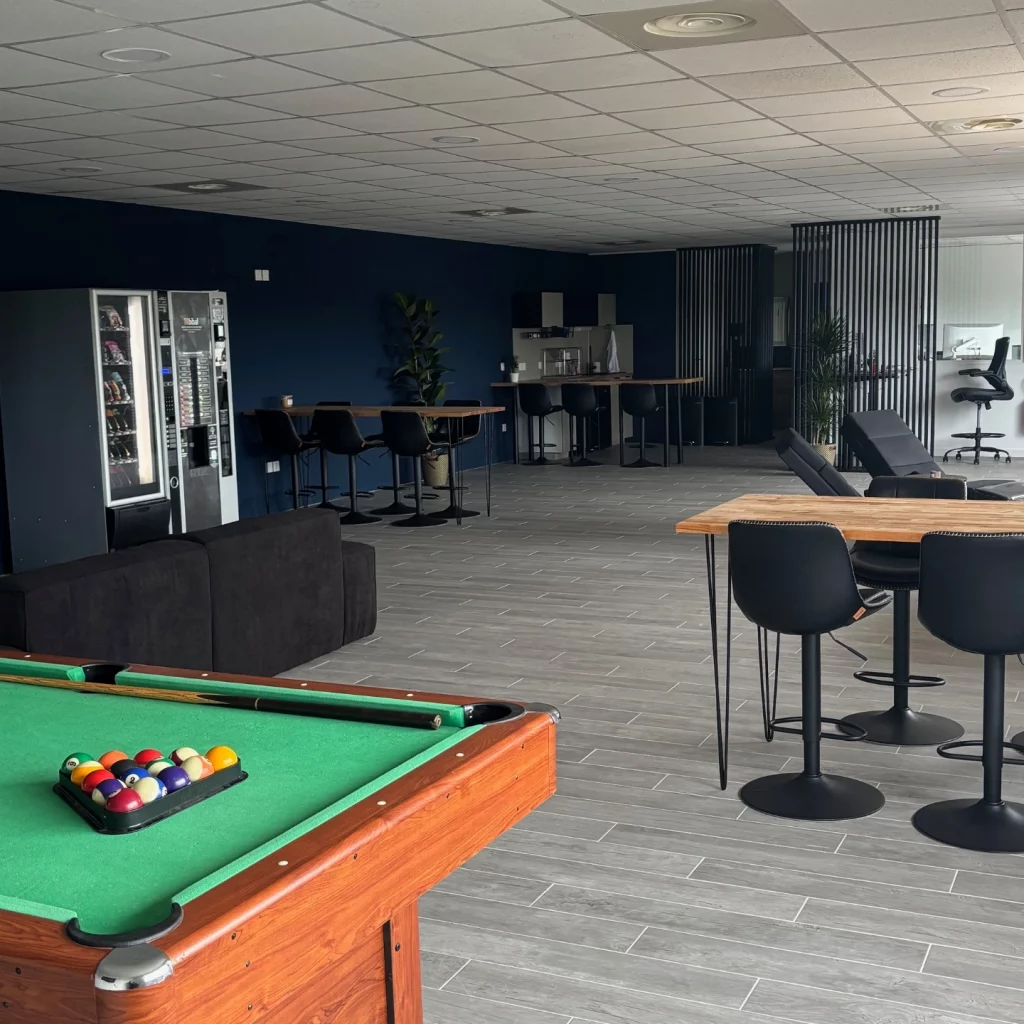 QG des VTC avec billard, coin travail, canapés, toilettes, coin cuisine et distributeurs de boissons chaudes et froides et snacks